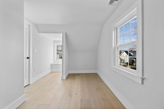 additional living space featuring vaulted ceiling, baseboards, visible vents, and light wood-type flooring