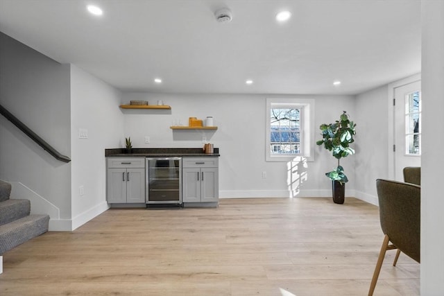 bar featuring recessed lighting, a bar, beverage cooler, and light wood finished floors