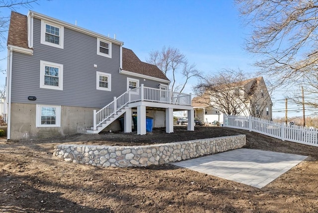 rear view of house with a patio, fence, roof with shingles, a wooden deck, and stairs