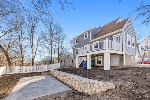 rear view of house featuring a shingled roof, a wooden deck, stairs, and fence