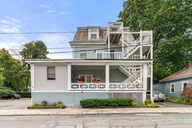 view of front of property with covered porch, stairway, and mansard roof