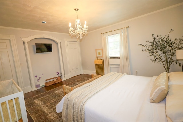 bedroom featuring an inviting chandelier, decorative columns, crown molding, and dark hardwood / wood-style flooring