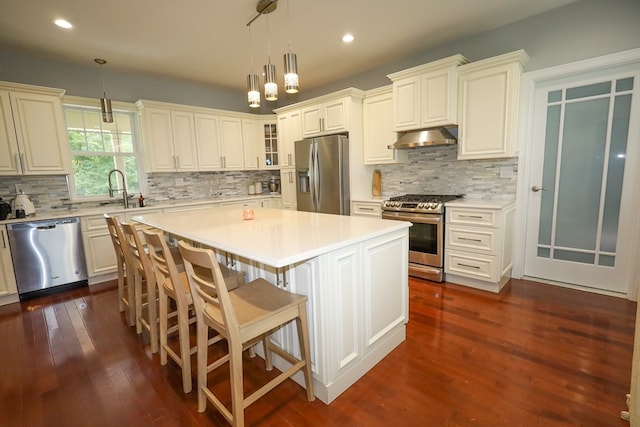 kitchen featuring pendant lighting, a center island, tasteful backsplash, stainless steel appliances, and dark hardwood / wood-style flooring