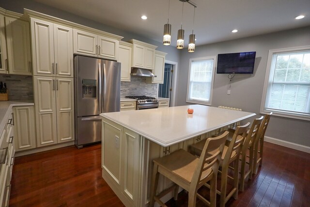 kitchen featuring stainless steel appliances, cream cabinets, and a wealth of natural light