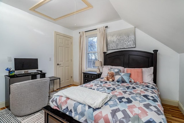 bedroom featuring vaulted ceiling, attic access, baseboards, and wood finished floors