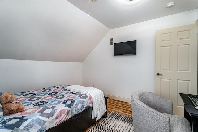 bedroom featuring baseboards, wood finished floors, and vaulted ceiling