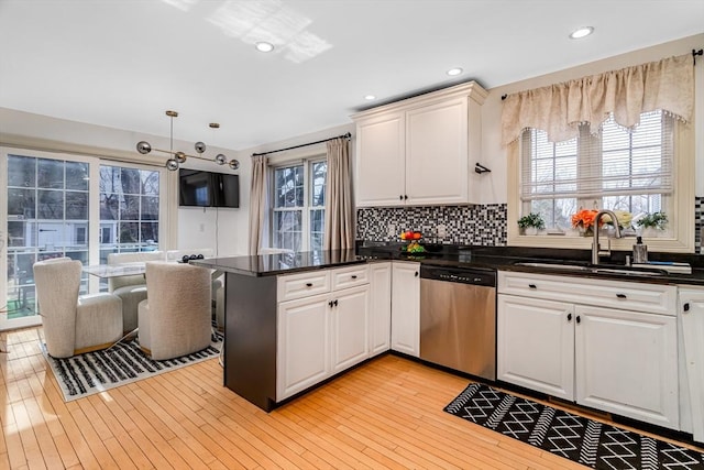 kitchen with dishwasher, white cabinets, light wood-style flooring, and a sink