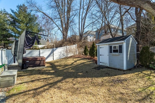 view of yard featuring an outbuilding, a fenced backyard, a shed, and a hot tub