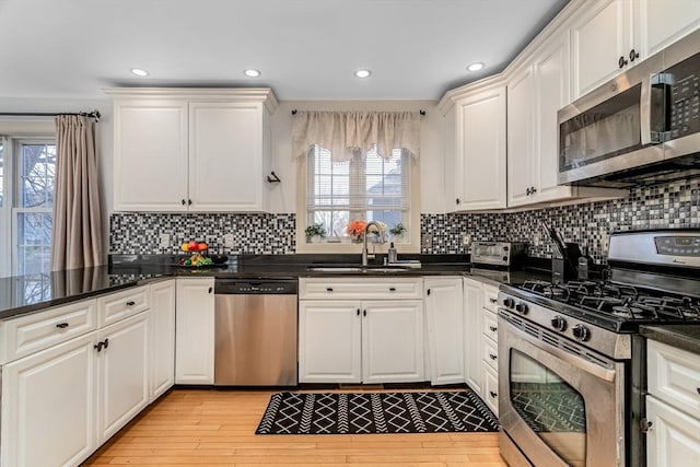 kitchen with a sink, white cabinets, light wood finished floors, and stainless steel appliances