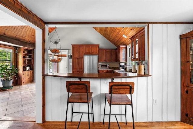 13 Clarks Rd, Amesbury, MA 01913 - kitchen with freestanding refrigerator, lofted ceiling, dark countertops, a peninsula, and glass insert cabinets