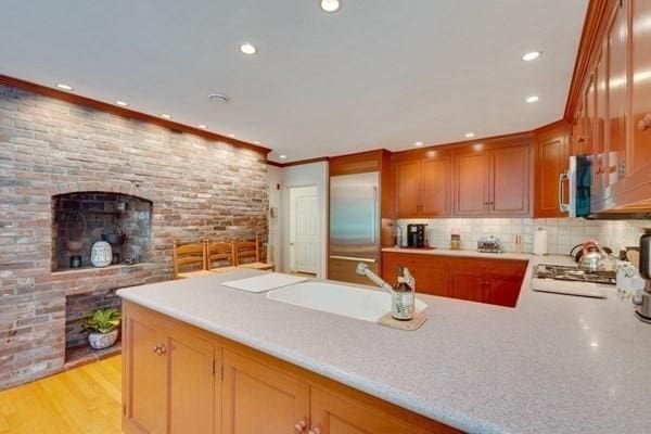 kitchen featuring recessed lighting, a peninsula, stainless steel appliances, a sink, and light countertops