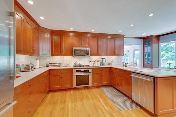 kitchen with a peninsula, brown cabinets, stainless steel appliances, and light countertops