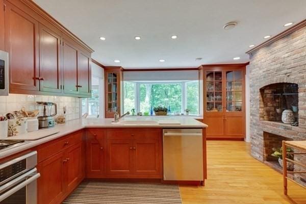 kitchen featuring stainless steel appliances, light countertops, light wood-style floors, ornamental molding, and a sink