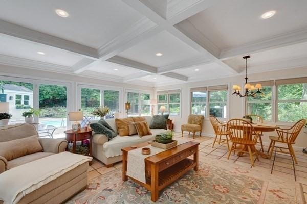 sunroom with beamed ceiling, plenty of natural light, coffered ceiling, and an inviting chandelier