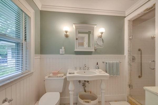 bathroom featuring a stall shower, wainscoting, toilet, and crown molding