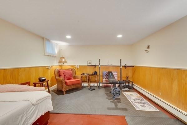 interior space featuring a wainscoted wall, a baseboard heating unit, carpet, and wooden walls