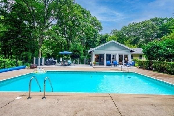 pool featuring an outbuilding, a patio, and fence