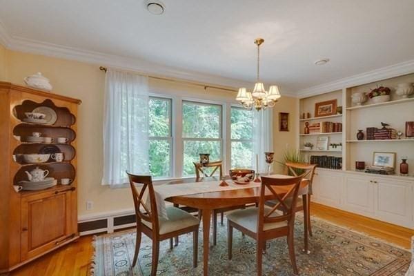 dining room featuring light wood finished floors, crown molding, and a notable chandelier