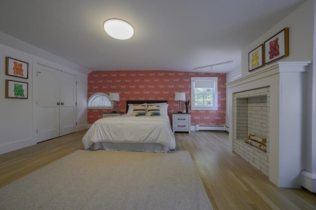 bedroom with light wood-type flooring and a baseboard heating unit