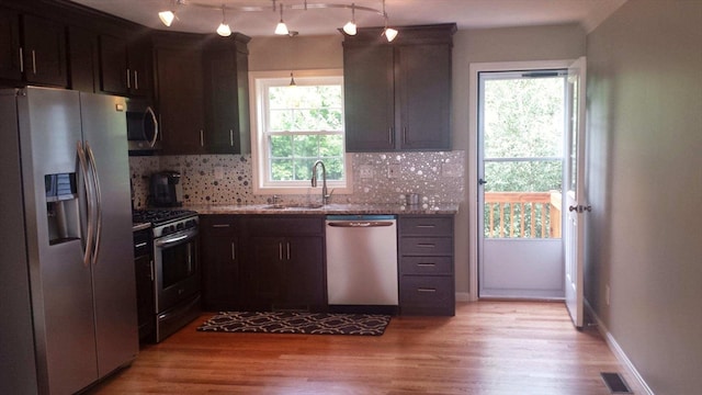 kitchen featuring light stone counters, appliances with stainless steel finishes, plenty of natural light, and light hardwood / wood-style floors