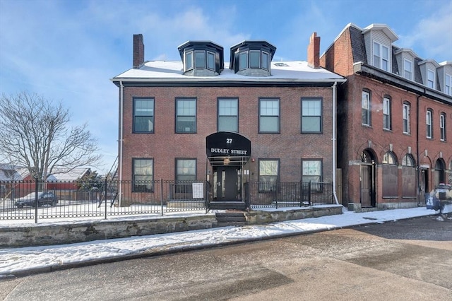 snow covered building featuring a fenced front yard