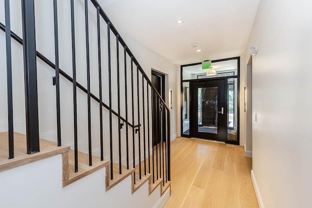 entryway with stairway, wood finished floors, and baseboards