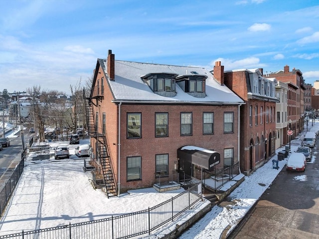 view of front of property with stairway, brick siding, and a chimney