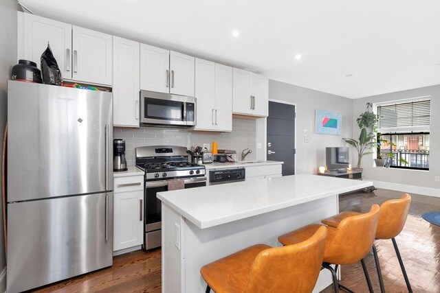 kitchen featuring decorative backsplash, white cabinets, stainless steel appliances, and light countertops