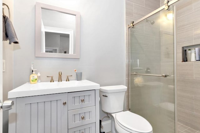 bathroom with vanity, a shower stall, and toilet