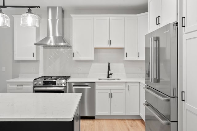 kitchen with decorative light fixtures, stainless steel appliances, wall chimney exhaust hood, backsplash, and sink