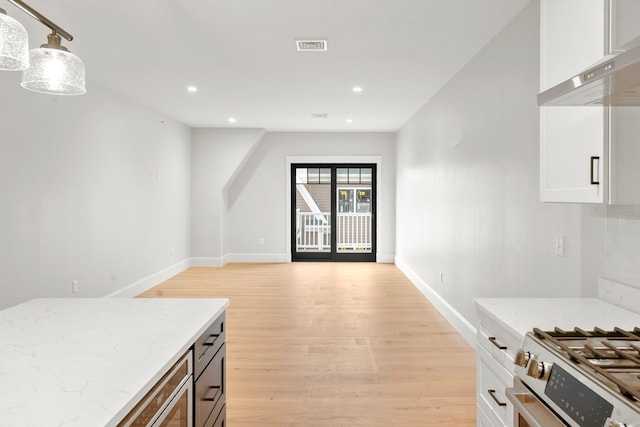 kitchen featuring white cabinets, light hardwood / wood-style floors, light stone countertops, and pendant lighting