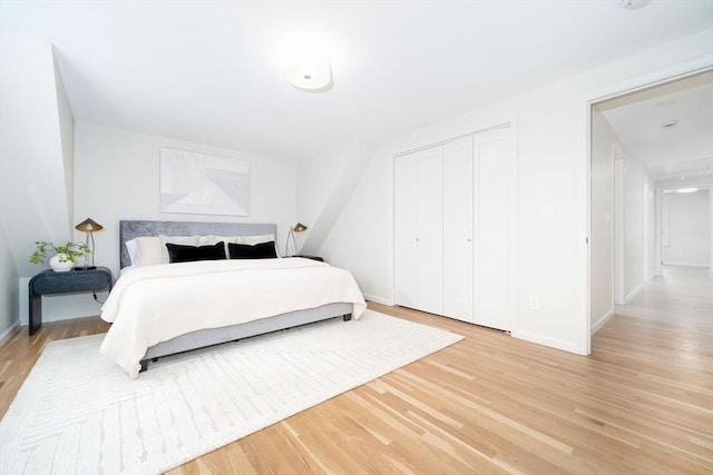 bedroom featuring light wood-style floors, baseboards, and a closet
