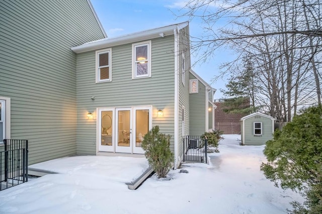 snow covered house with a storage unit, an outbuilding, and a patio area