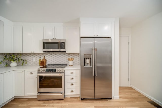 kitchen with stainless steel appliances, light wood-style flooring, light countertops, and white cabinets