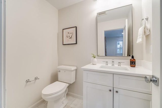 half bath with baseboards, toilet, vanity, and marble finish flooring