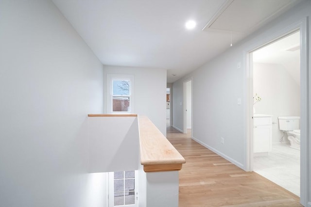 hallway with attic access, light wood-style floors, and baseboards
