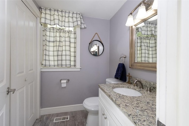 bathroom featuring toilet, wood finished floors, visible vents, baseboards, and vanity