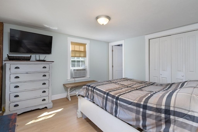 bedroom with cooling unit, a closet, baseboards, and light wood-style floors
