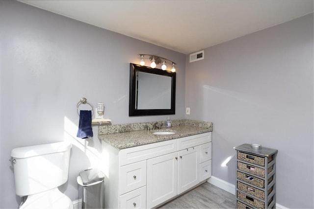 bathroom with toilet, wood finished floors, visible vents, baseboards, and vanity
