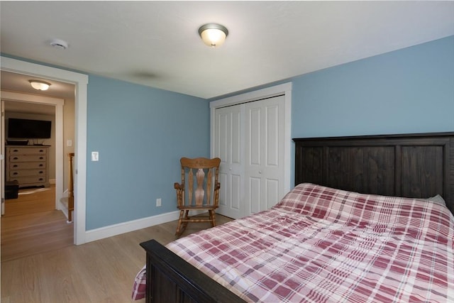 bedroom featuring baseboards, light wood-type flooring, and a closet