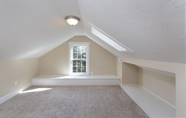 additional living space with carpet, baseboards, and lofted ceiling with skylight