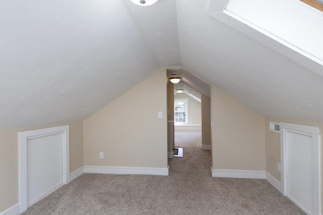 additional living space with vaulted ceiling, carpet, baseboards, and visible vents