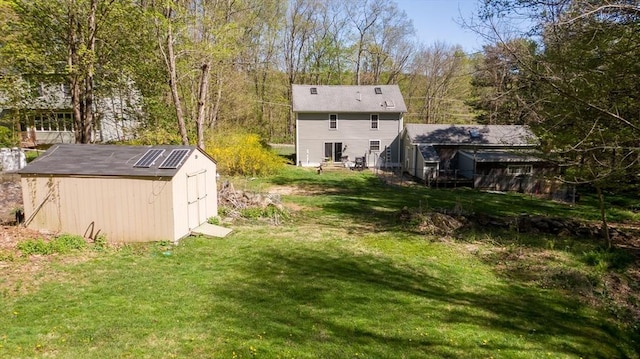 rear view of house with a yard, an outbuilding, and a storage shed