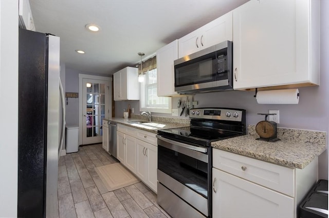 kitchen featuring white cabinetry, stainless steel appliances, light wood-style flooring, and a sink