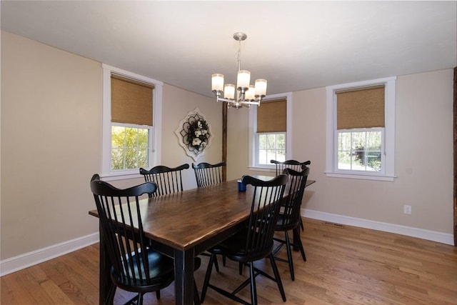 dining room with a chandelier, light wood-style flooring, baseboards, and visible vents
