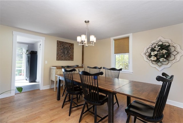 dining space featuring an inviting chandelier, baseboards, and light wood-type flooring