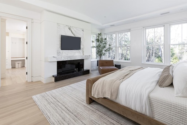 bedroom featuring a high end fireplace, visible vents, and wood finished floors
