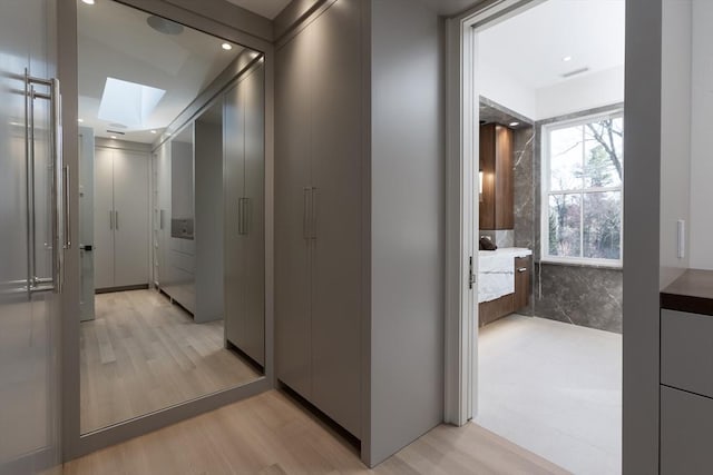 hallway with a skylight, recessed lighting, visible vents, and light wood-style floors
