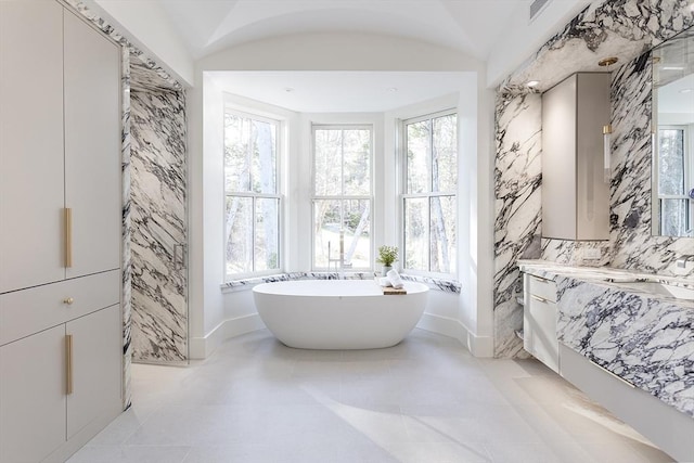 bathroom with visible vents, baseboards, a sink, and a soaking tub