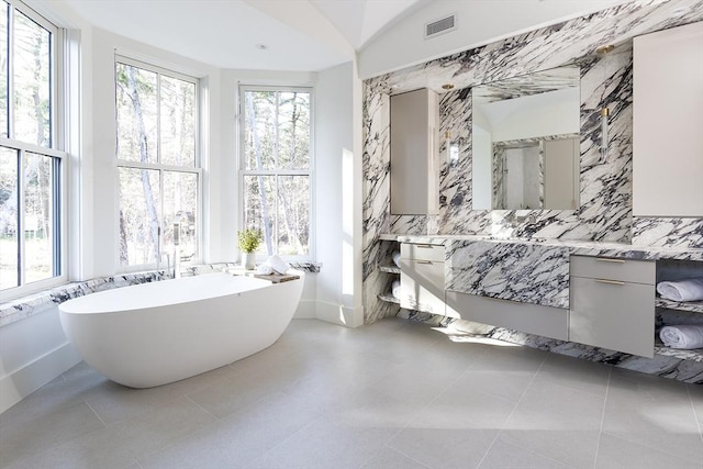 bathroom with a freestanding bath, vanity, visible vents, and a healthy amount of sunlight